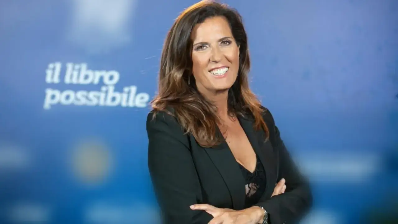 Donna sorridente con giacca nera, sullo sfondo la scritta "il libro possibile". Sembra che voglia raccontare una storia, come un pappagallo rosella parla.