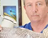 Un uomo con un falco in braccio, probabilmente un veterinario per uccelli, in un ambiente che ricorda uno studio medico.